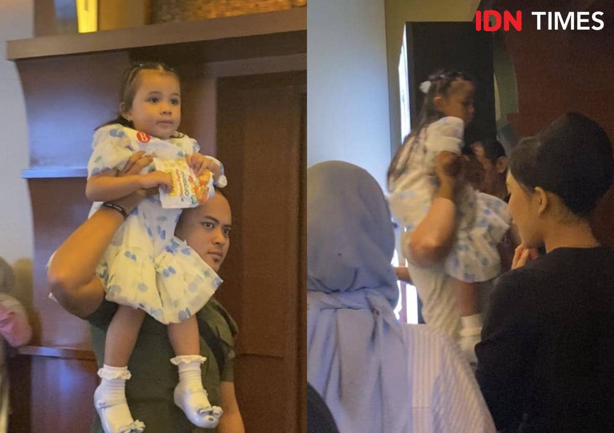 Seorang pria menggendong anak kecil mengenakan gaun putih bermotif biru saat menghadiri special screening film Moana live-action di Jakarta.