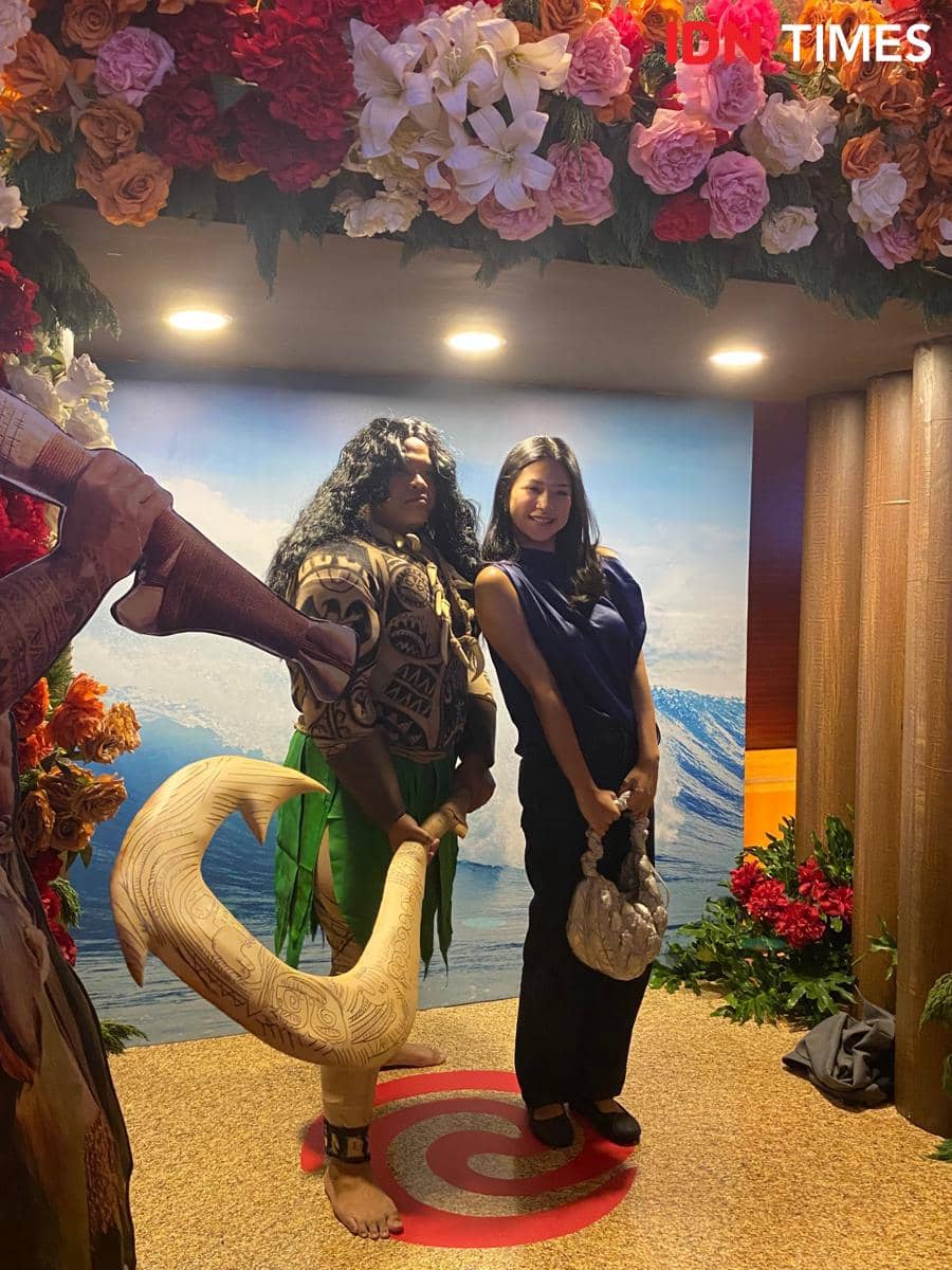 Seorang artis berpose bersama keluarga di acara special screening film Moana live-action di Jakarta dengan latar dekorasi bunga dan laut.
