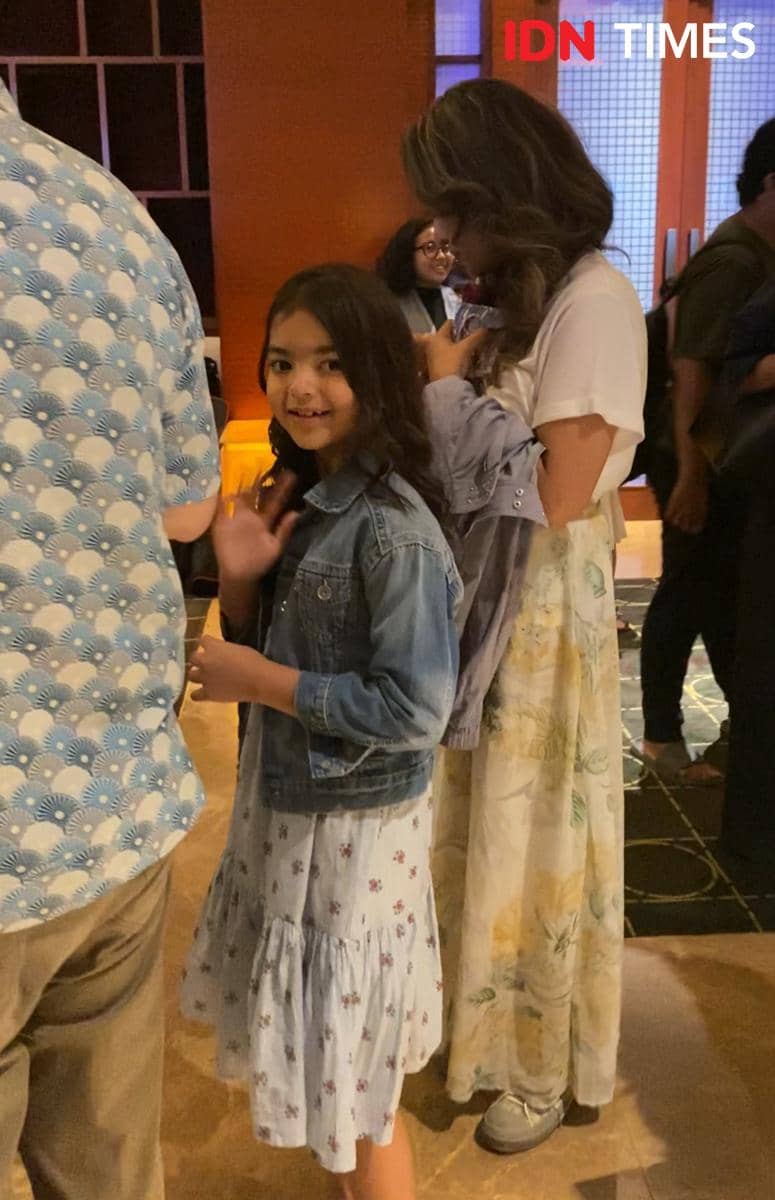 Seorang anak perempuan mengenakan jaket denim dan gaun bermotif bunga melambaikan tangan di acara special screening Moana live-action di Jakarta.