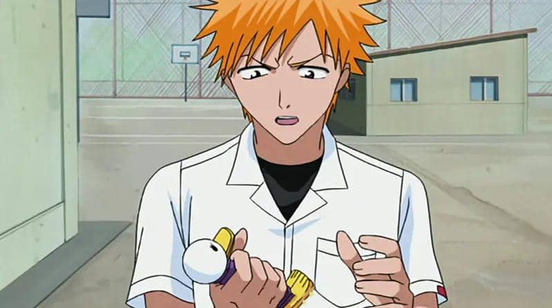 Ichigo dengan rambut oranye mengenakan seragam sekolah putih sedang memegang boneka Gikon di area sekolah.