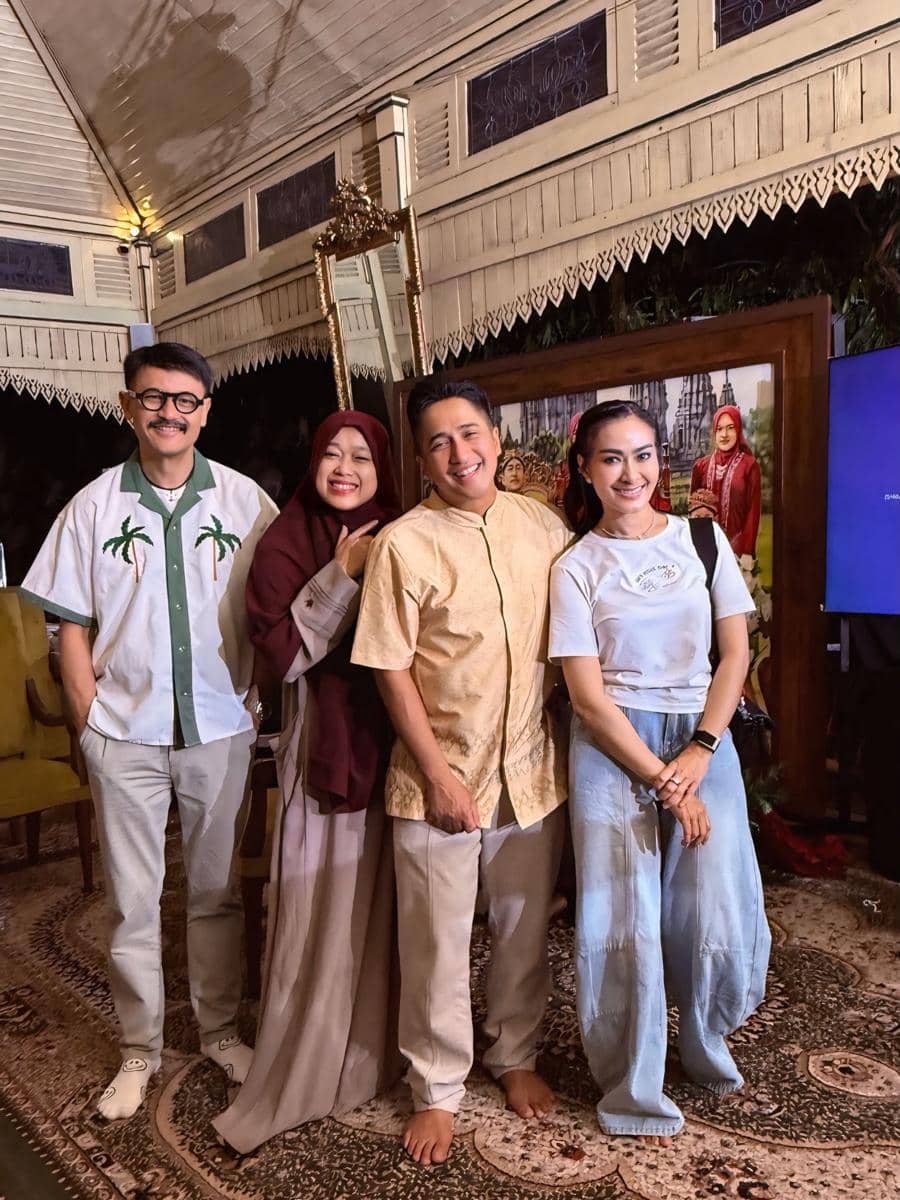 Empat orang berdiri bersama di acara perayaan ulang tahun pernikahan ke-19, tersenyum di dalam ruangan dengan dekorasi tradisional.