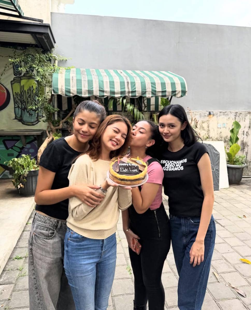 Empat remaja perempuan berpose bersama di luar ruangan, salah satunya memegang kue ulang tahun bertuliskan pesan untuk Electra Leslie.