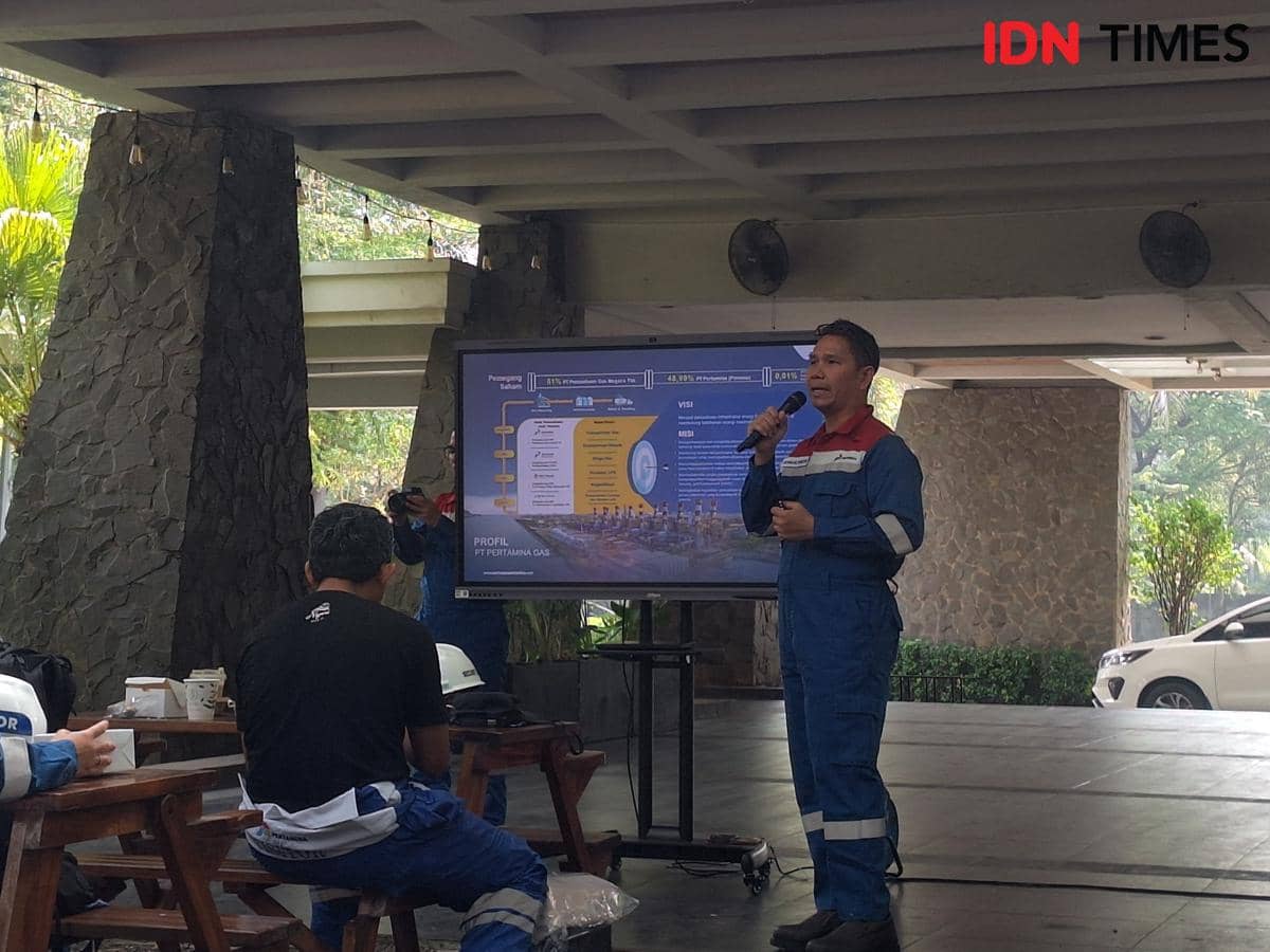 Seorang pria berseragam biru memberikan presentasi di depan layar besar yang menampilkan profil PT Pertamina Gas di Stasiun Kompresor Gas Tegal Gede, Jawa Barat.