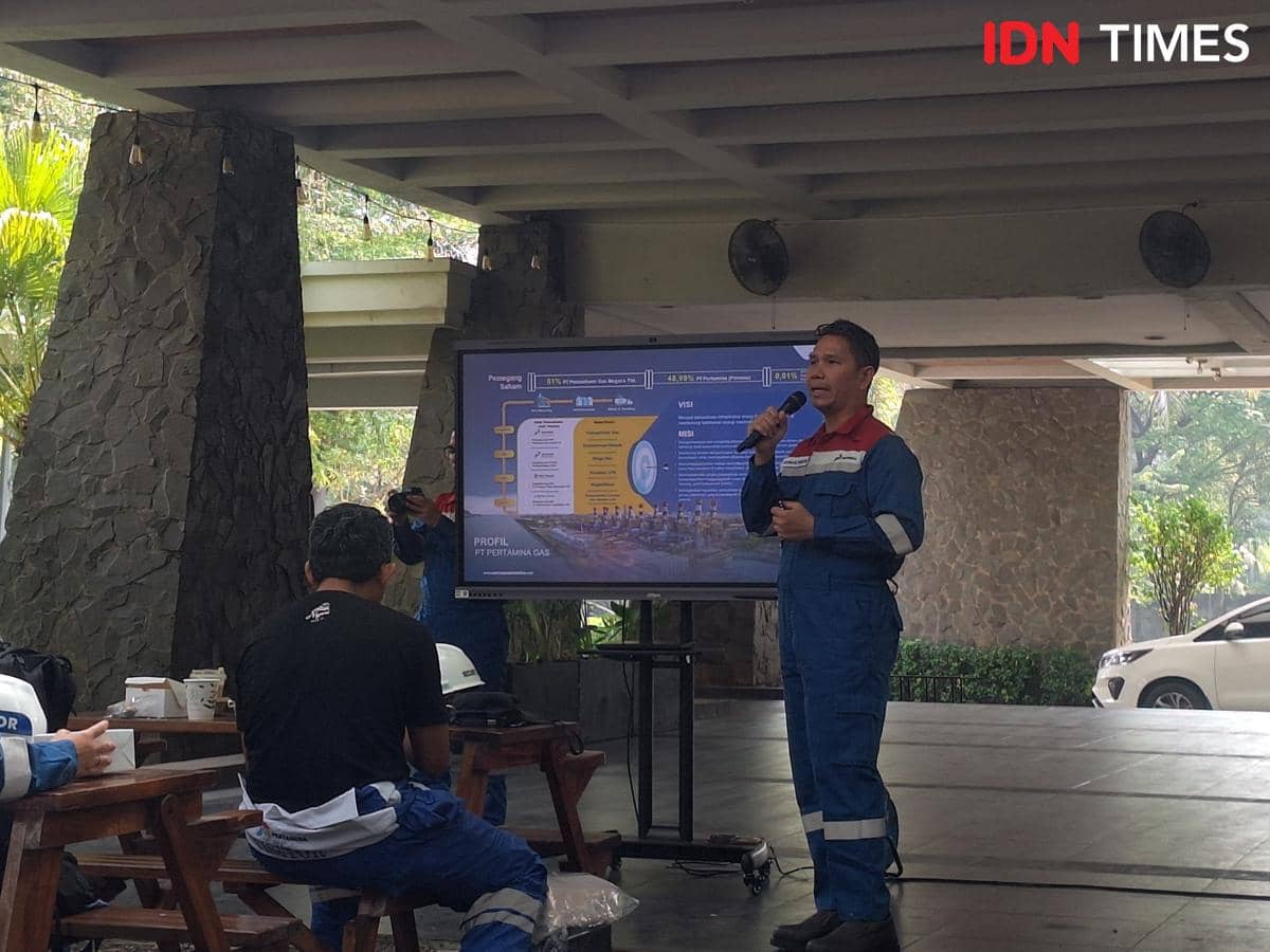 Seorang pria berseragam biru memberikan presentasi di depan layar besar yang menampilkan profil PT Pertamina Gas di Stasiun Kompresor Gas Tegal Gede, Jawa Barat.
