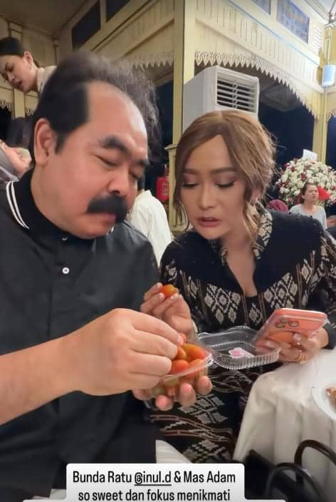 Sepasang tamu duduk berdampingan di acara perayaan ulang tahun pernikahan ke-19, menikmati hidangan sambil berbincang akrab.