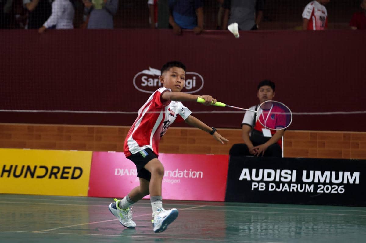 Seorang anak mengenakan seragam merah putih sedang memukul shuttlecock di lapangan bulu tangkis saat Audisi Umum PB Djarum 2026 di Pekanbaru.