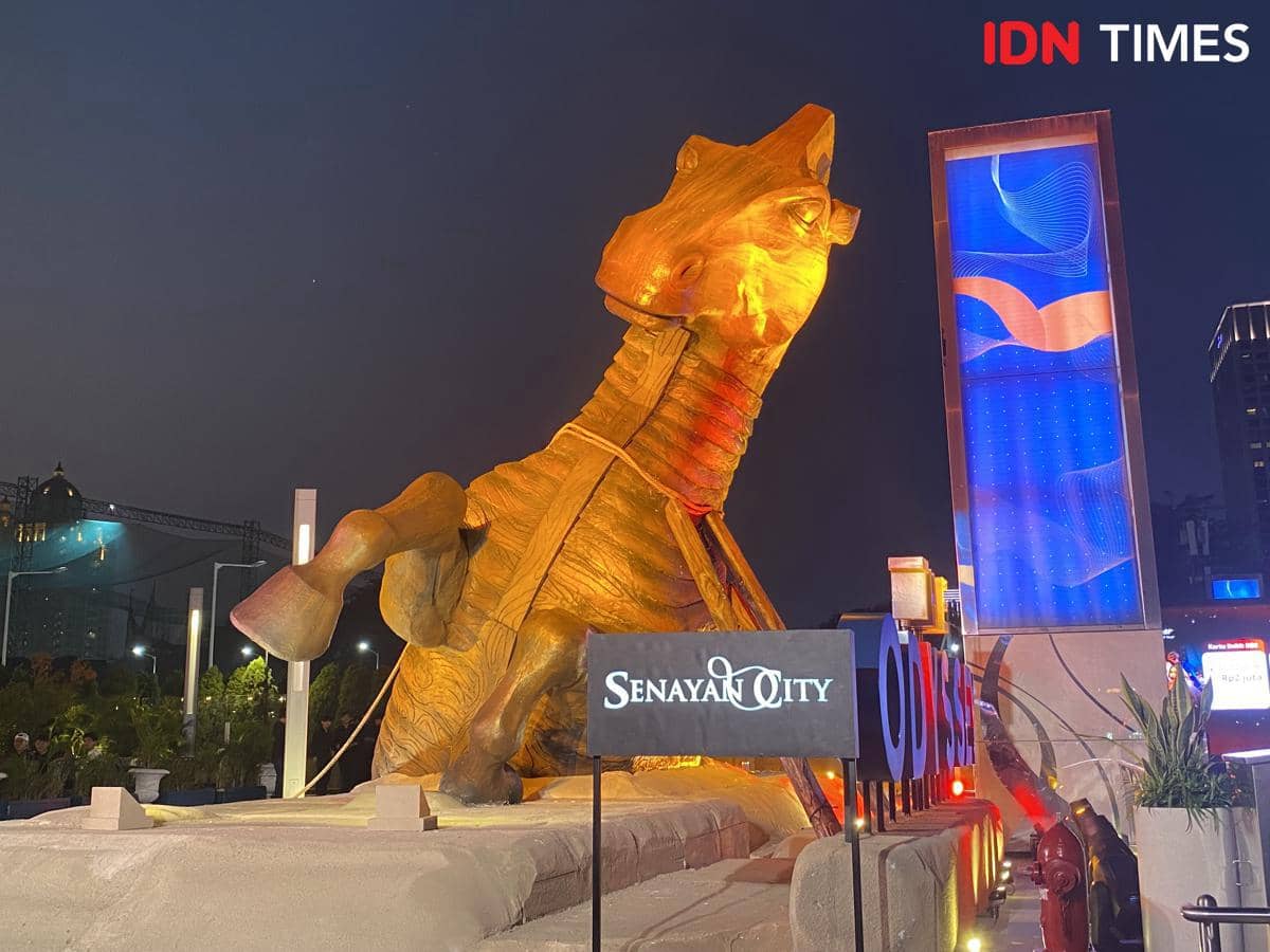 Instalasi Kuda Troya raksasa berwarna emas dari The Odyssey berdiri megah di area luar Senayan City, Jakarta pada malam hari.