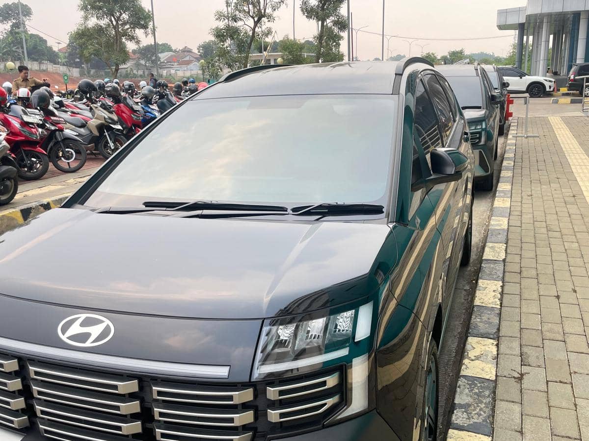 Deretan mobil dinas berwarna gelap yang disewa Pemkot Tangsel terparkir di area luar gedung dengan latar parkiran motor.
