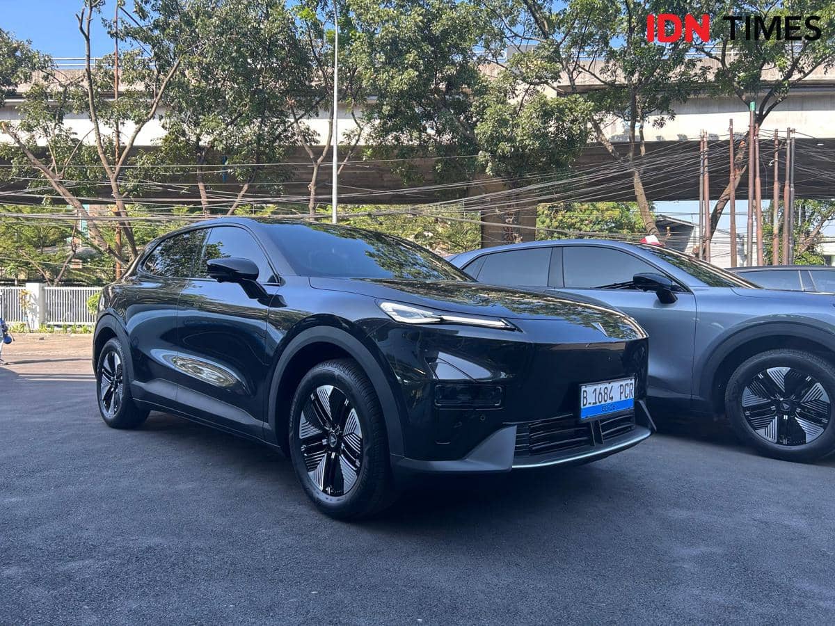 Mobil listrik Changan Deepal S05 berwarna hitam sedang diparkir di area terbuka dengan latar pepohonan dan jalan layang.