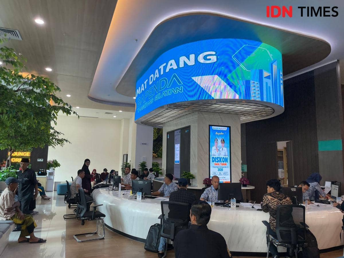 Suasana pelayanan di kantor Bapenda Tangerang Selatan dengan petugas melayani warga di meja layanan dan layar digital besar di atasnya.