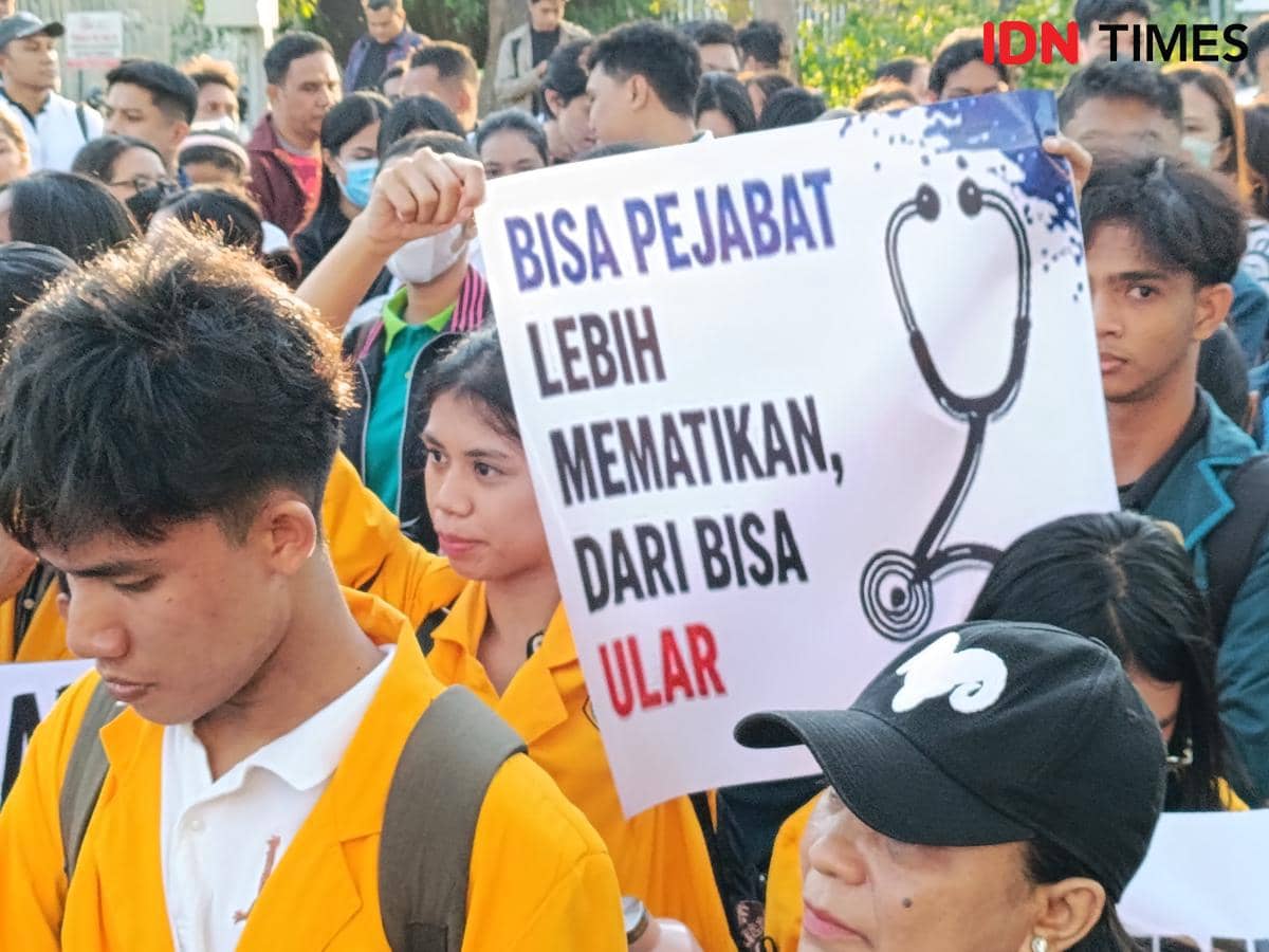 Sekelompok dokter, tenaga kesehatan, dan mahasiswa mengenakan jas kuning berunjuk rasa di DPRD NTT sambil membawa poster bertuliskan kritik terhadap pejabat.