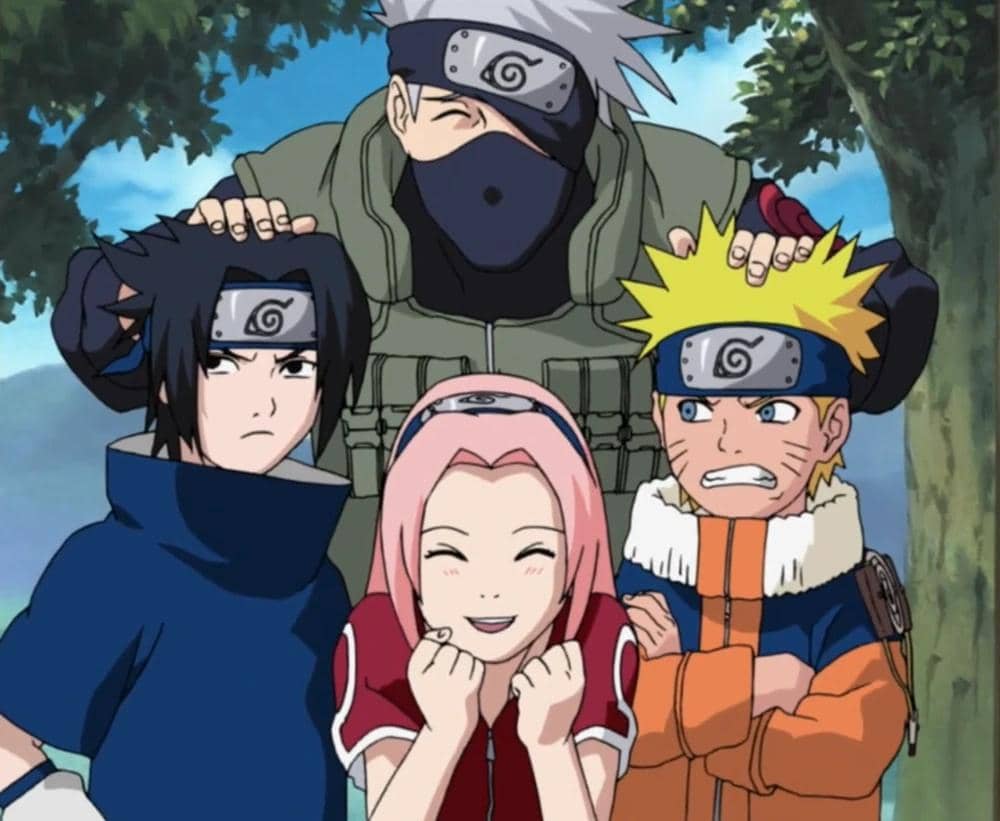 Empat karakter anime Naruto, terdiri dari tiga murid muda dan satu guru, berpose bersama di luar ruangan dengan ekspresi berbeda.