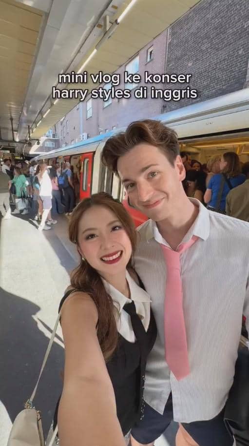 Sepasang pria dan wanita berpose sambil tersenyum di peron stasiun kereta di Inggris sebelum menonton konser Harry Styles.