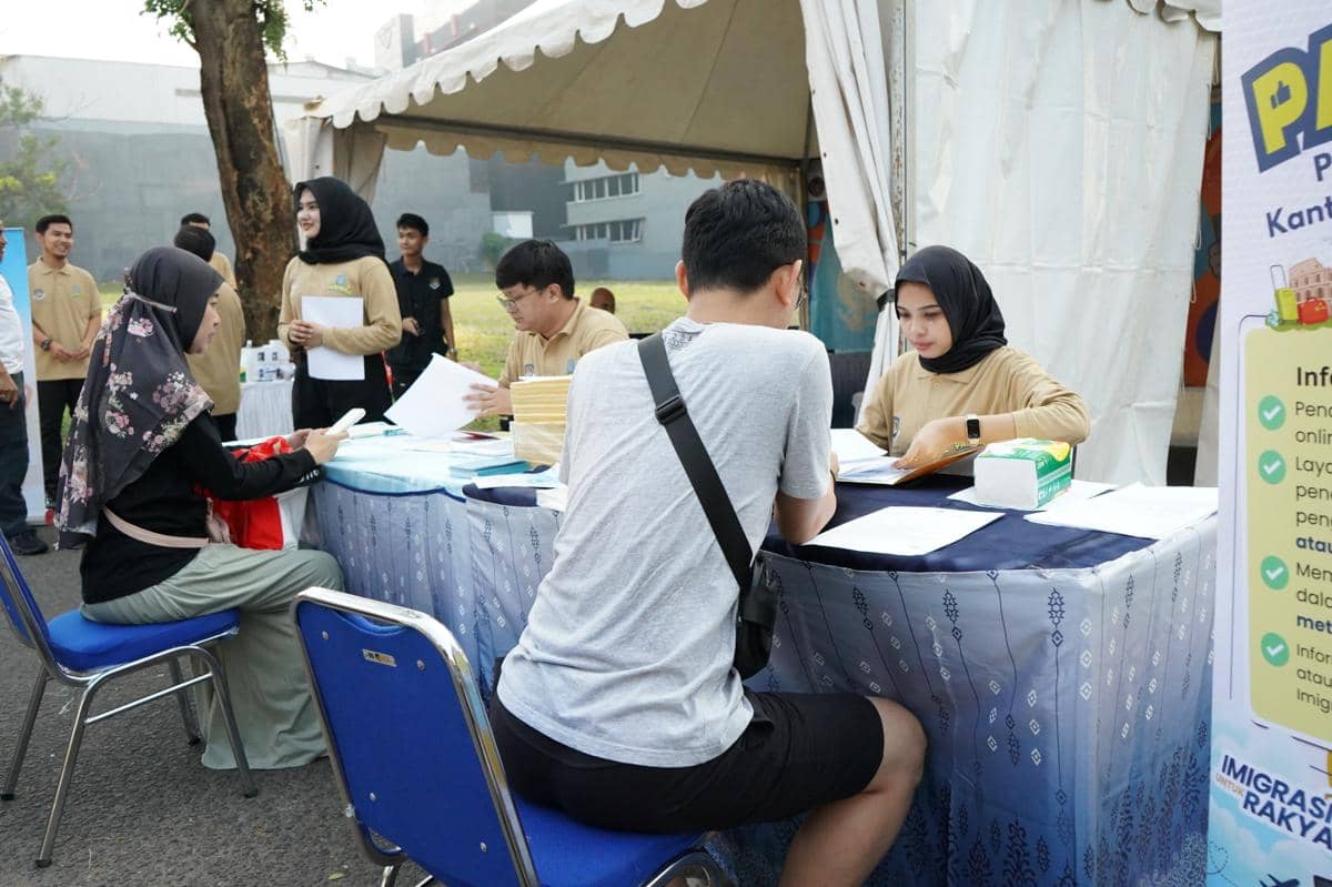Petugas imigrasi melayani masyarakat yang mengurus paspor di meja layanan luar ruangan Kantor Imigrasi Tangerang.
