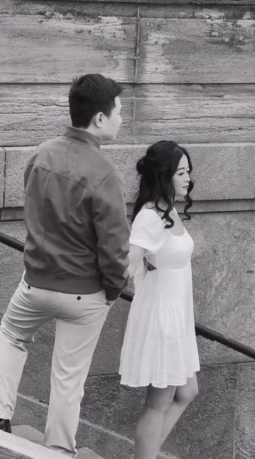 Sepasang pria dan wanita berjalan menuruni tangga batu dalam sesi foto prewedding bergaya monokrom dengan latar dinding batu.