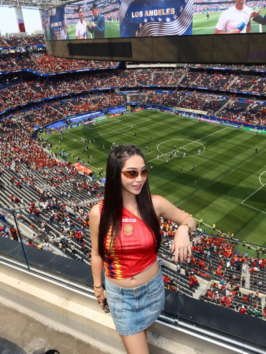 Seorang wanita mengenakan jersey tim Spanyol berpose di stadion besar di Los Angeles saat pertandingan Spanyol melawan Belgia.