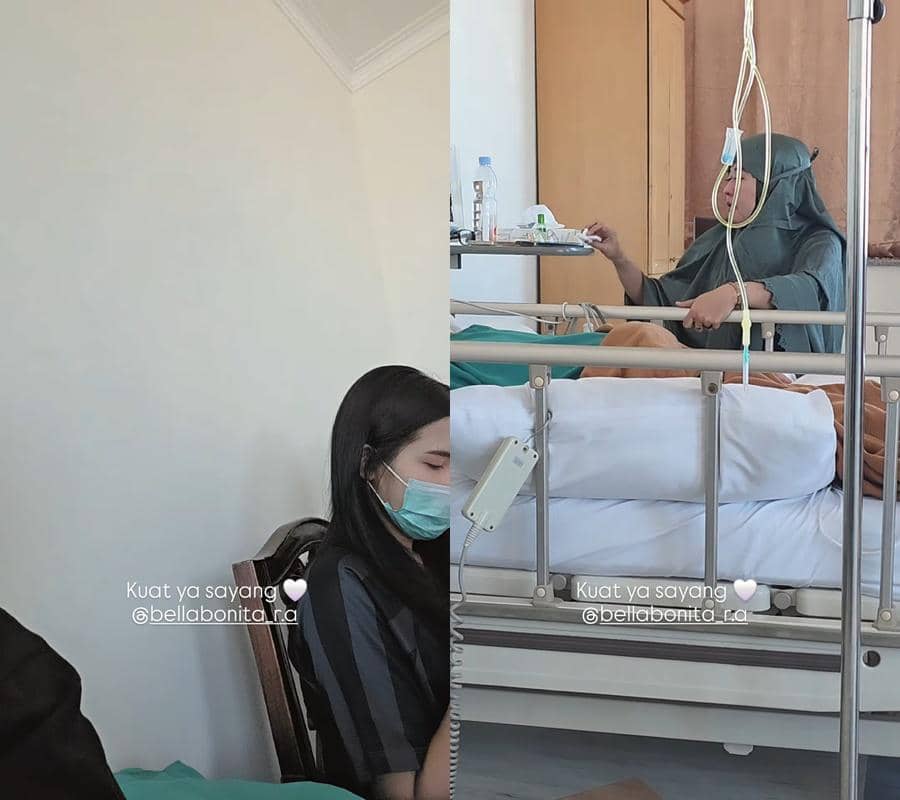 Seorang perempuan mengenakan masker duduk di samping tempat tidur rumah sakit, sementara seorang pasien berkerudung terbaring di ranjang dengan infus.
