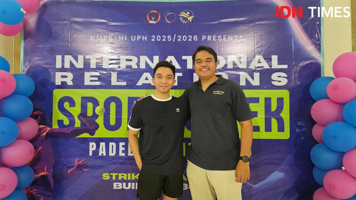 Dua peserta berpose di depan backdrop International Relations Sports Week 2026 Universitas Pelita Harapan di ACE Padel, Tangerang.