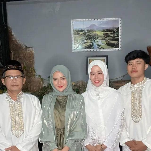 Empat orang berpose bersama mengenakan busana muslim, dua perempuan berhijab di tengah diapit oleh dua pria dengan baju koko putih.