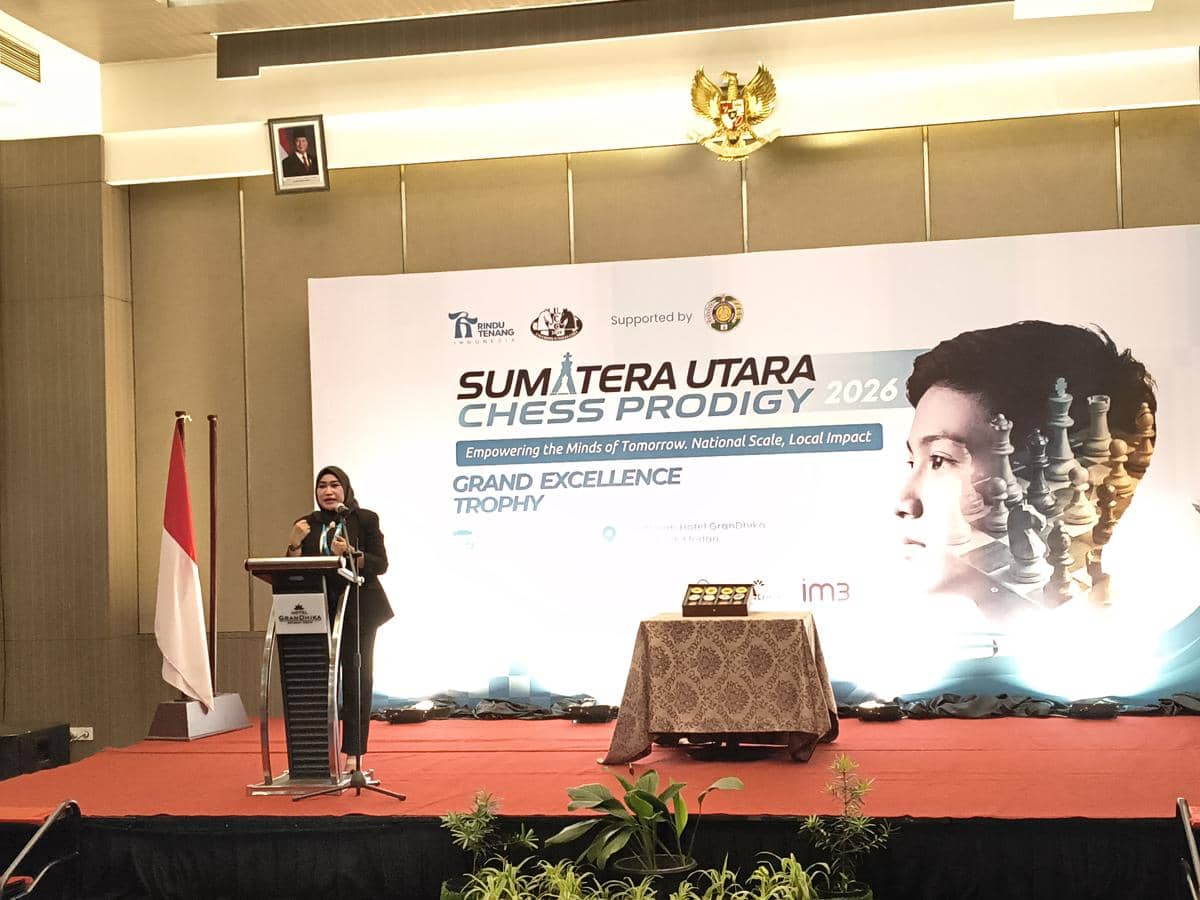 Seorang pembicara berdiri di podium memberikan sambutan pada acara Sumatera Utara Chess Prodigy 2026 di sebuah ruangan konferensi.