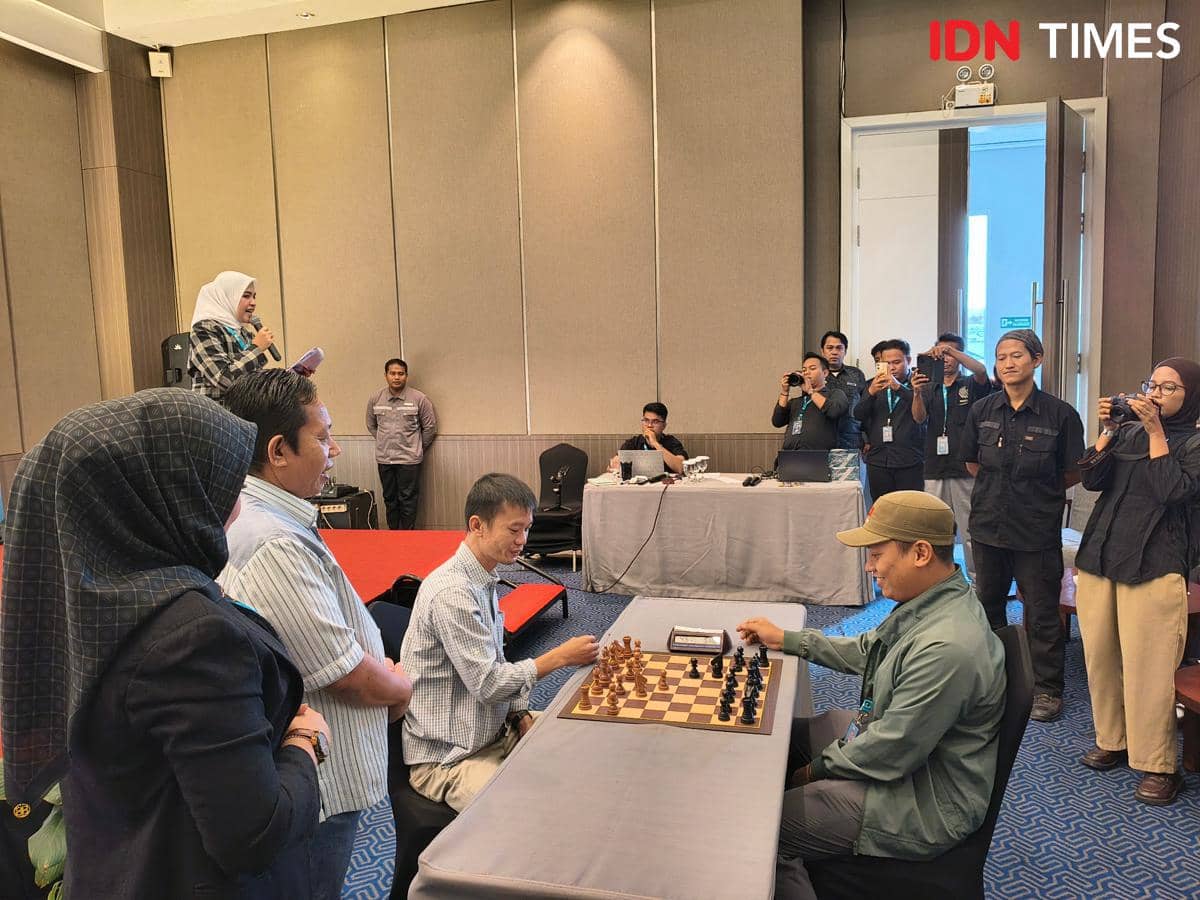 Dua peserta duduk berhadapan memainkan catur di meja turnamen, disaksikan panitia dan jurnalis di Hotel Grandhika Medan.