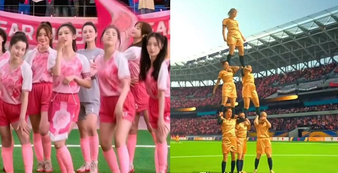 Pemain sepak bola wanita mengenakan seragam merah muda dan tim lawan berseragam emas membentuk menara manusia di stadion penuh penonton.