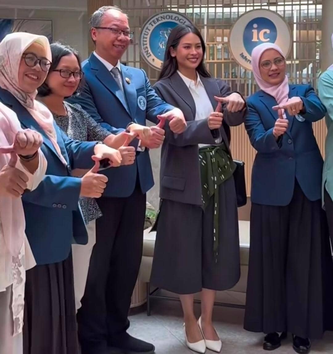 Seorang tamu kehormatan berpose bersama dosen dan staf Institut Teknologi Bandung mengenakan jas biru di area kampus.