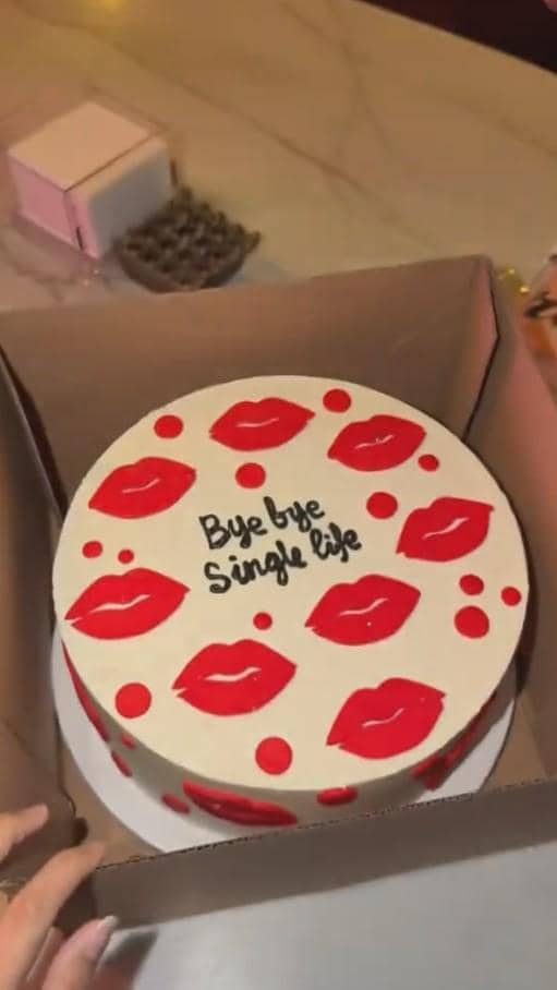 Kue bertema bridal shower dengan tulisan 'Bye bye single life' dan hiasan cetakan bibir merah di atas meja marmer.