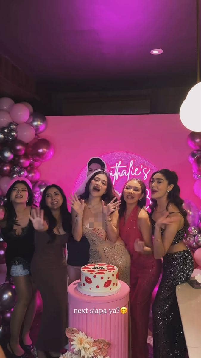 Beberapa wanita berpose ceria di pesta bridal shower dengan dekorasi balon merah muda dan kue bertema bibir di atas meja.