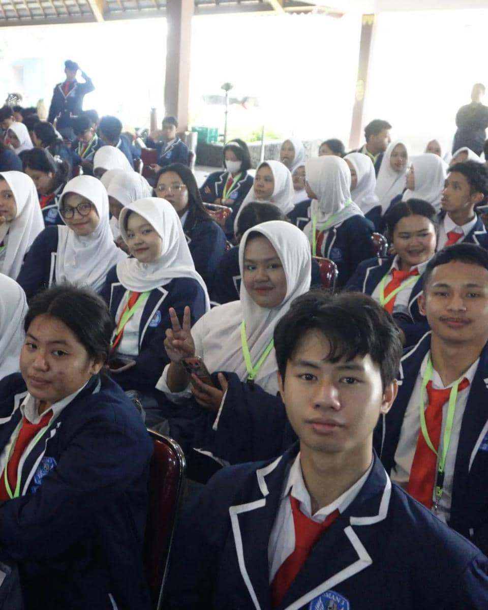 Sekelompok siswa mengenakan seragam biru dengan dasi merah dan lanyard hijau duduk bersama di acara Kafka Clash of Champions Season 3.
