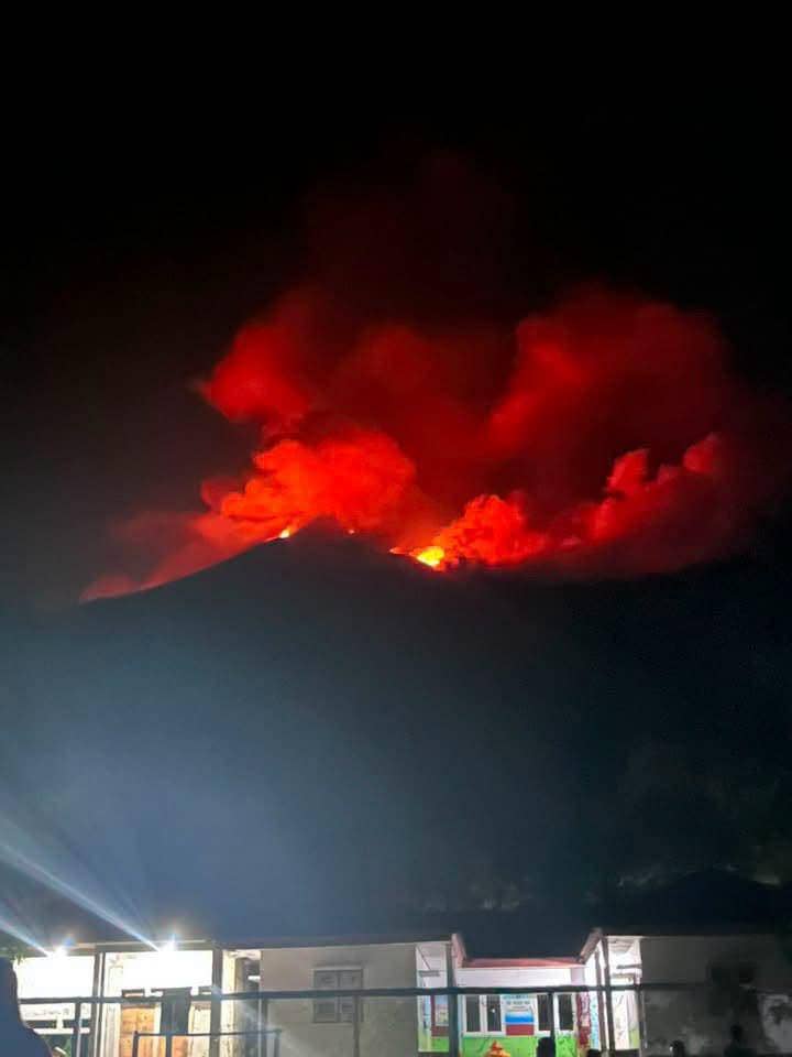 Erupsi Gunung Karangetang di Siau, Sulawesi Utara, memancarkan cahaya merah menyala di langit malam yang terlihat dari rumah warga.