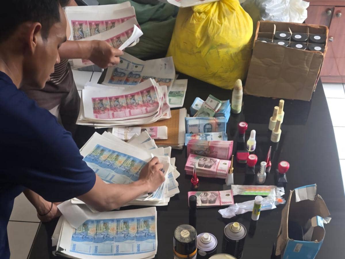 Petugas memeriksa lembaran uang palsu berbagai nominal bersama peralatan dan bahan produksi di atas meja di Pakuhaji, Tangerang.