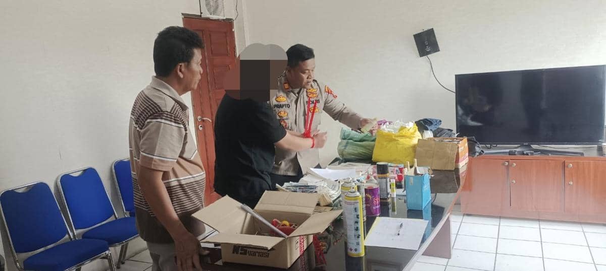 Petugas kepolisian memeriksa barang bukti di atas meja bersama dua pria di sebuah ruangan dengan televisi dan kursi biru di Pakuhaji.