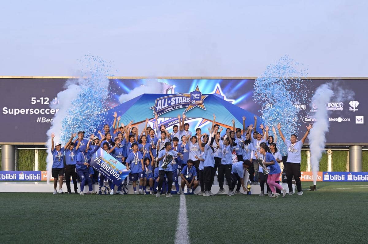 Tim sepak bola merayakan kemenangan di panggung final Hydroplus Soccer League 2025/26 dengan konfeti biru dan piala juara.