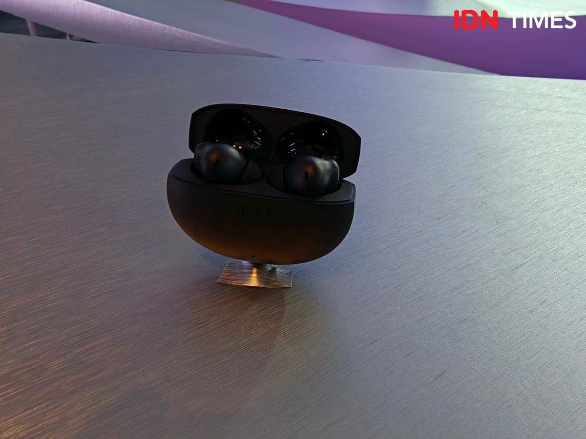 Earbud nirkabel OPPO Enco Air5 berwarna hitam ditempatkan di atas permukaan meja logam dengan pencahayaan lembut.
