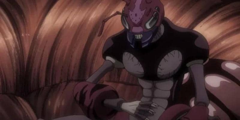 Ratu Chimera Ant dengan tubuh besar berwarna ungu dan hitam duduk di dalam sarang dengan pencahayaan redup dari anime Hunter x Hunter.