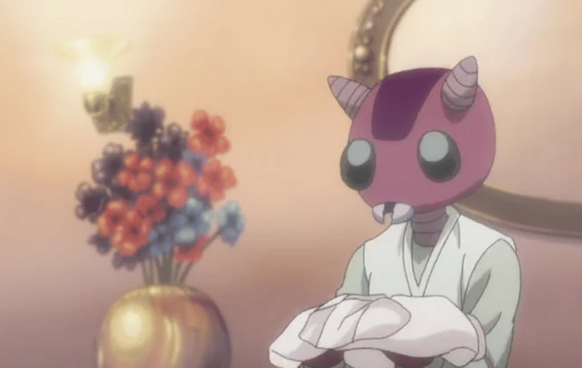 Karakter Shidore dari anime Hunter x Hunter duduk di ruangan dengan pencahayaan hangat dan vas bunga berwarna-warni di latar belakang.