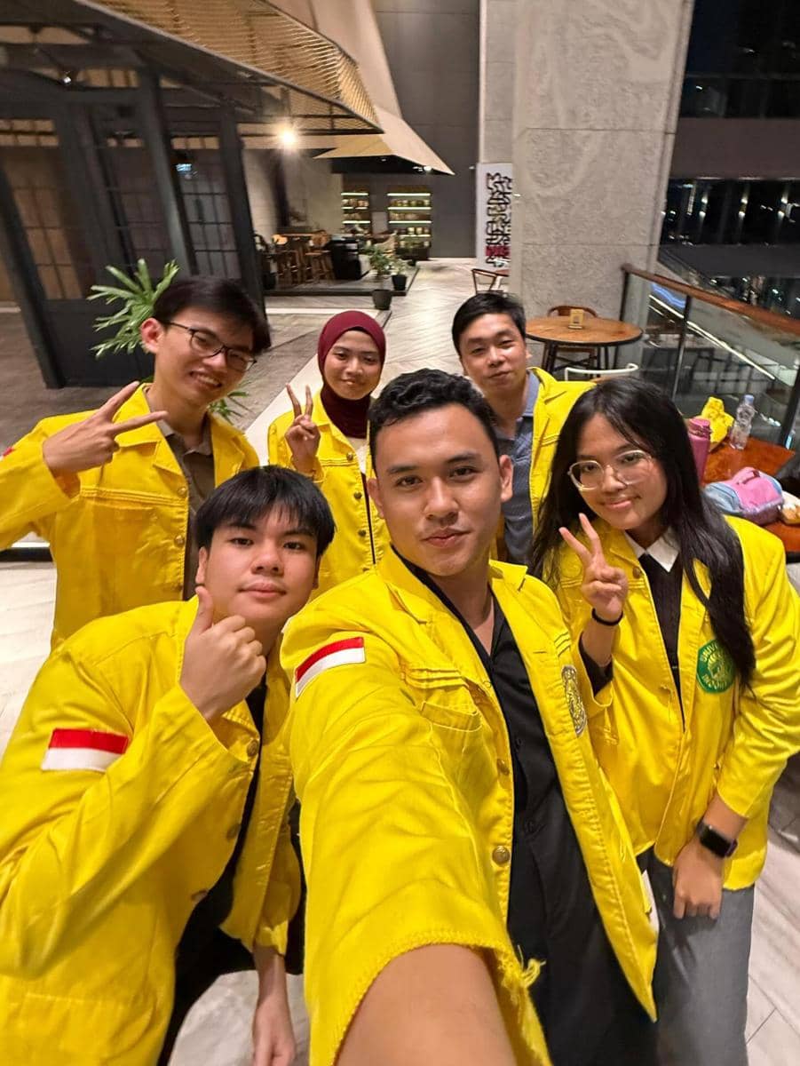 Sekelompok peserta Clash of Champions Season 3 mengenakan jaket kuning berfoto bersama di area indoor dengan suasana santai.