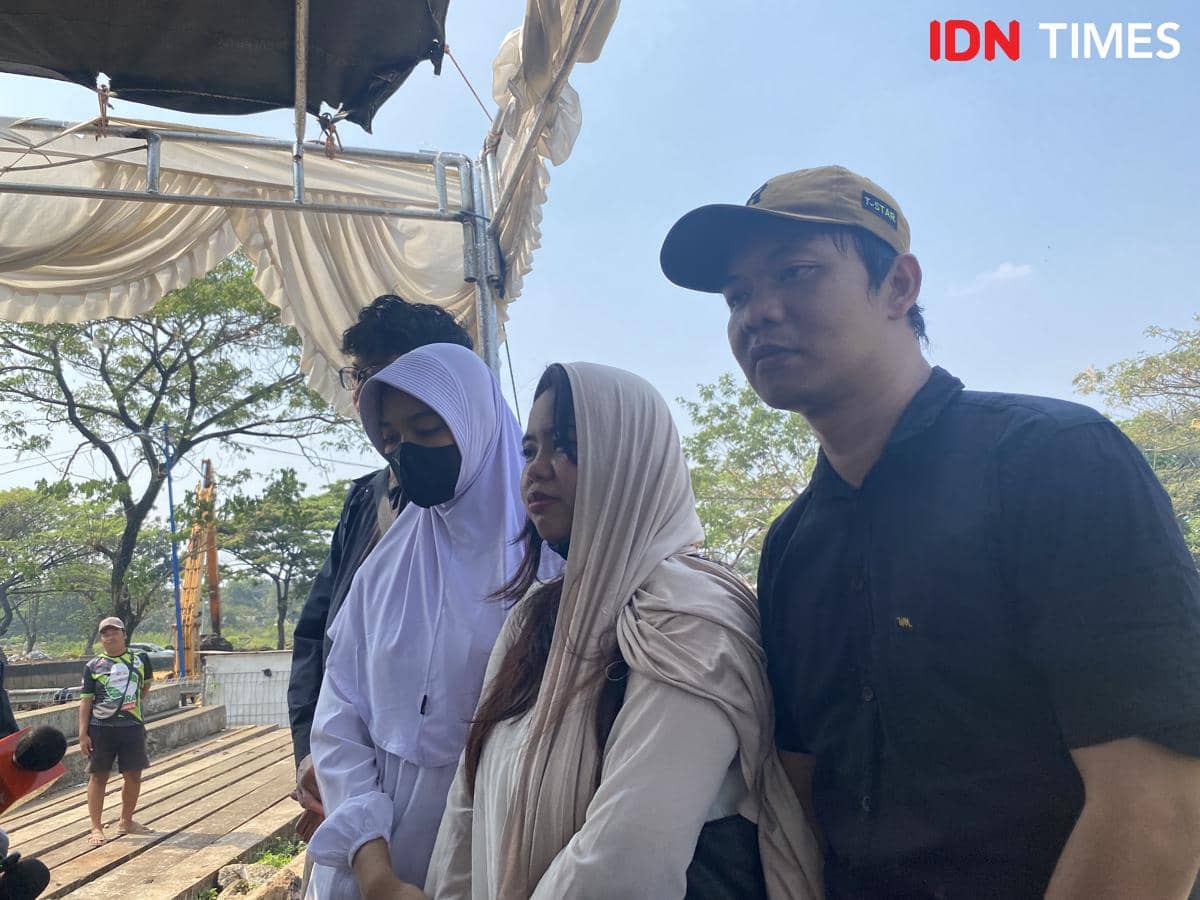 Beberapa orang berpakaian hitam dan putih berdiri dengan ekspresi sedih di area pemakaman Tanah Kusir, Jakarta Selatan.