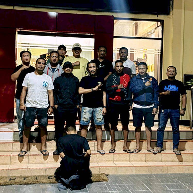 Tim Polda NTT berpose bersama seorang pria yang berlutut di depan mereka setelah penangkapan polisi gadungan di Kupang.