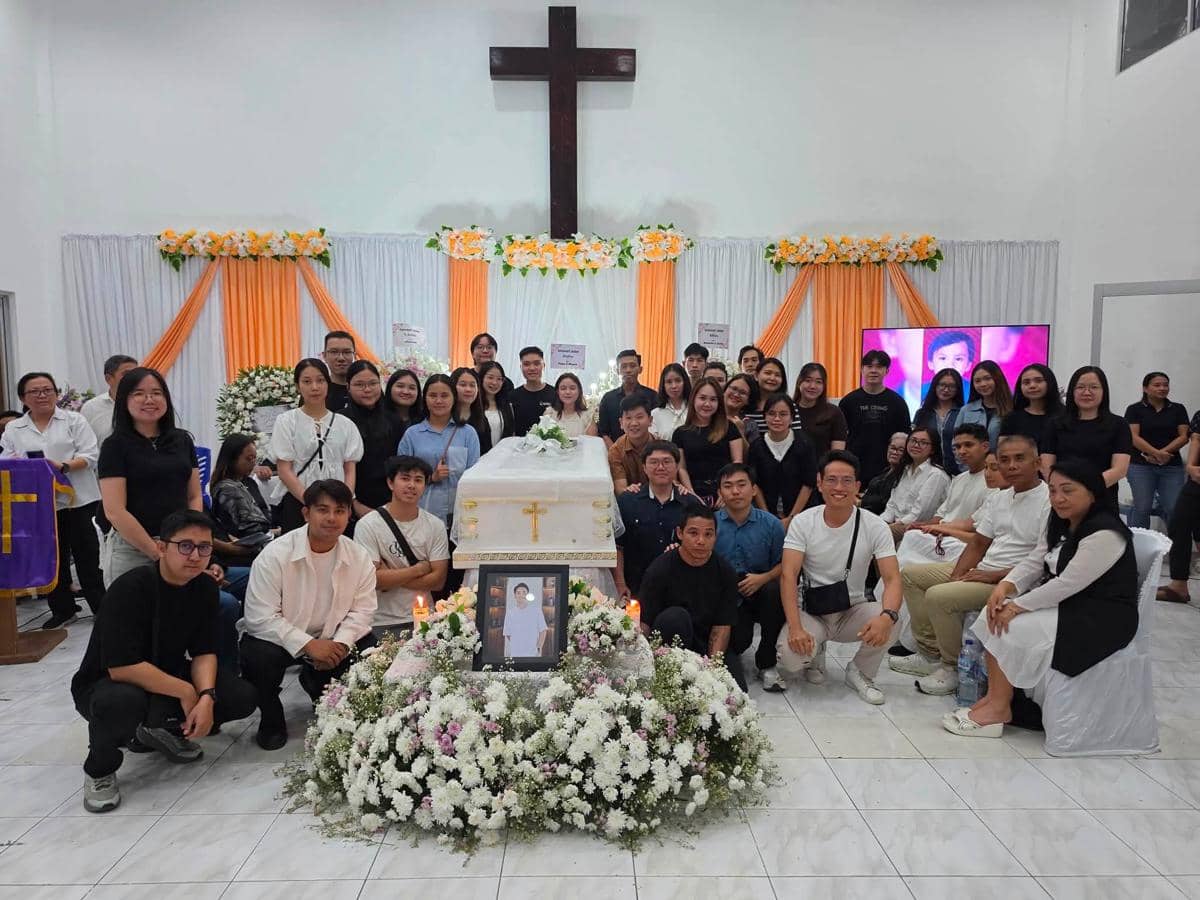 Sekelompok pelayat berfoto bersama di sekitar peti jenazah yang dihiasi bunga di sebuah gereja saat ibadah pemakaman di Manado.