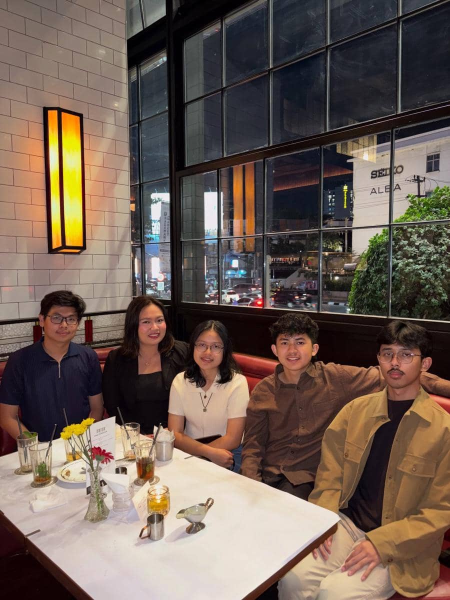 Lima peserta Clash of Champions Season 3 duduk bersama di meja restoran dengan suasana malam kota terlihat melalui jendela besar.