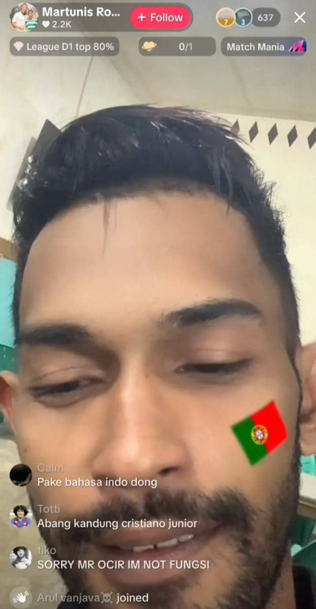 Seorang pria melakukan siaran langsung di TikTok dengan stiker bendera Portugal di pipinya dan beberapa komentar penonton terlihat di layar.