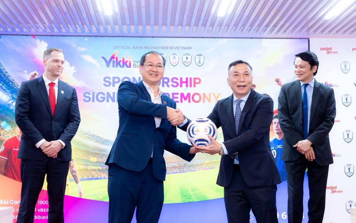 Perwakilan Vietjet dan ASEAN United FC berjabat tangan sambil memegang bola dalam acara penandatanganan kemitraan resmi.