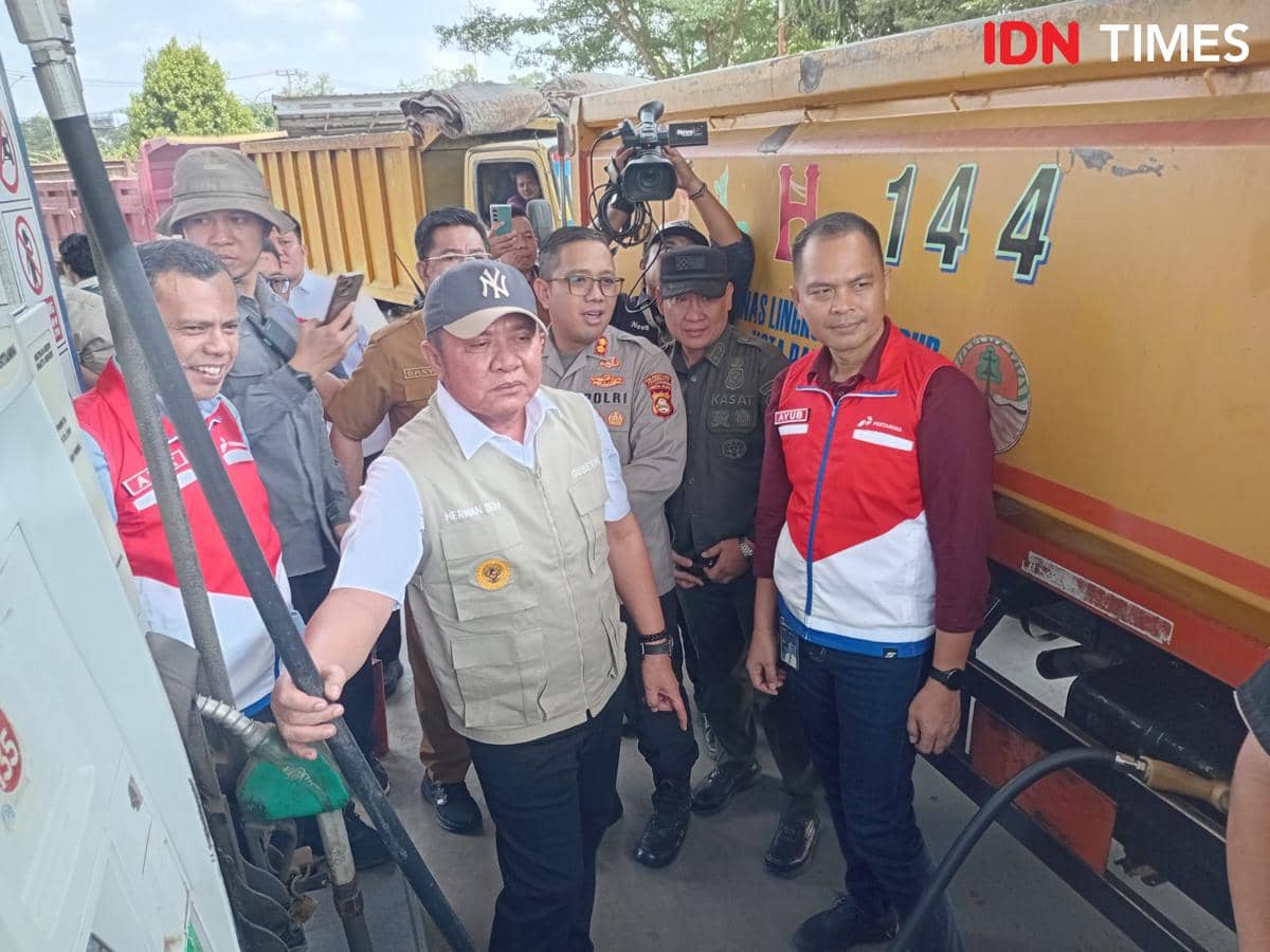 Seorang pejabat daerah bersama petugas Pertamina dan aparat kepolisian memeriksa proses pengisian bahan bakar ke truk tangki di SPBU.