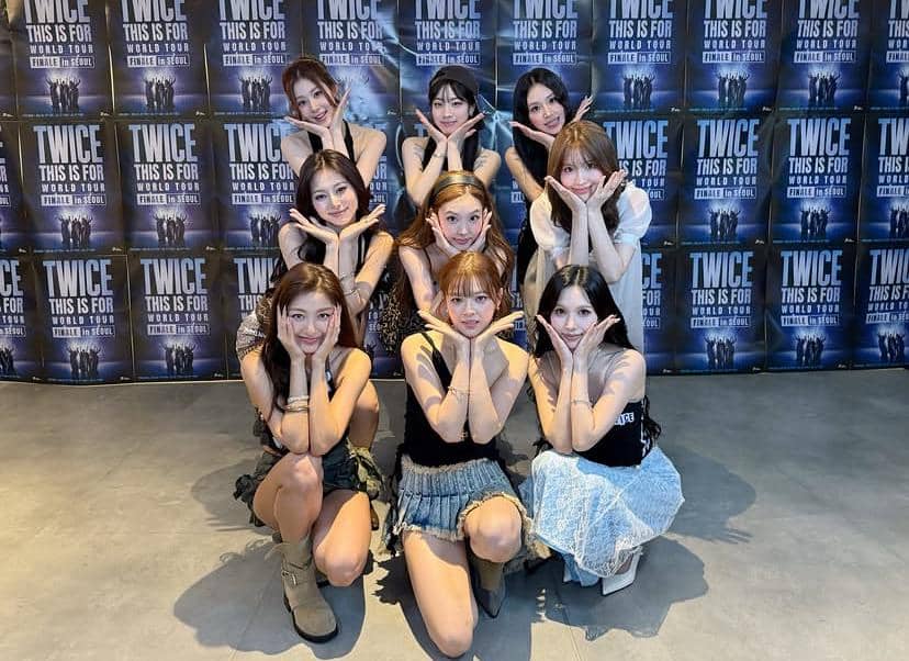 Sembilan anggota grup musik TWICE berpose bersama di depan latar bertuliskan 'TWICE This Is For World Tour Finale in Seoul'.