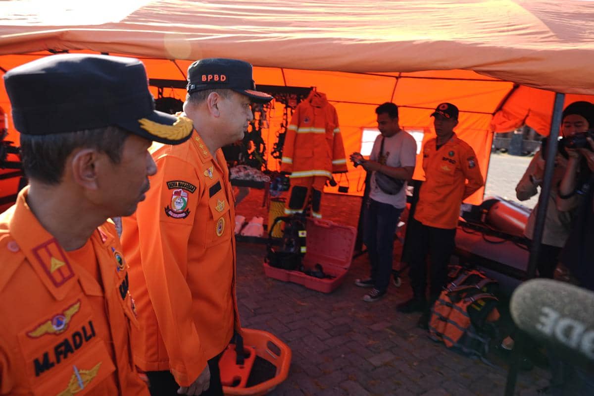 Petugas BPBD berseragam oranye meninjau peralatan evakuasi di bawah tenda oranye saat Apel Kesiapsiagaan Bencana di Makassar.