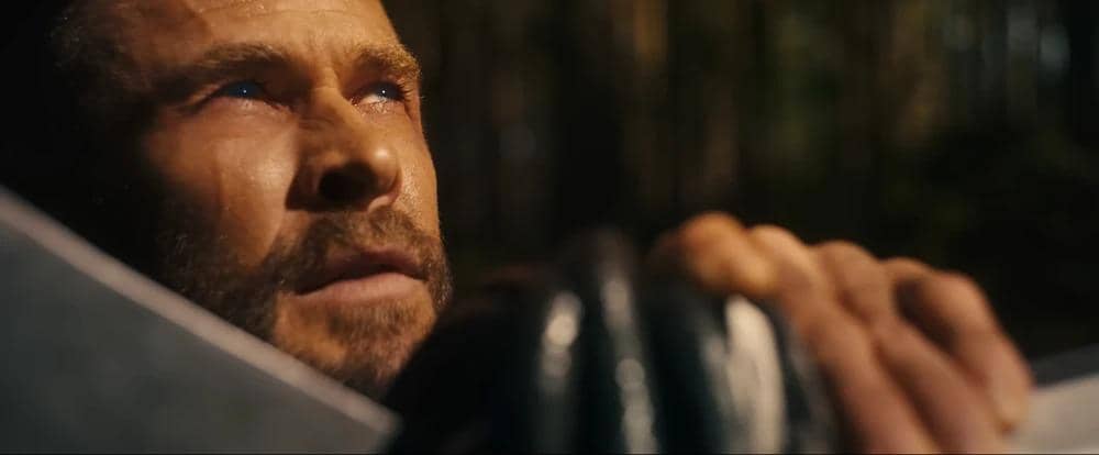 Seorang pria berwajah serius memandang ke atas sambil memegang gagang senjata besar dalam cuplikan trailer Avengers: Doomsday.