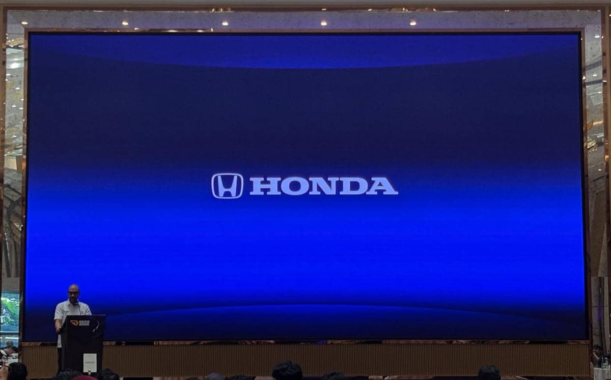 Seorang pembicara berdiri di podium di depan layar besar menampilkan logo Honda dengan latar biru pada acara GIIAS 2026.