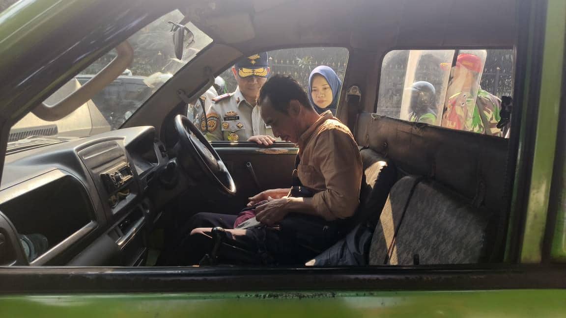 Seorang sopir angkutan umum menyerahkan surat-surat kendaraan kepada petugas Dinas Perhubungan saat razia di jalan.
